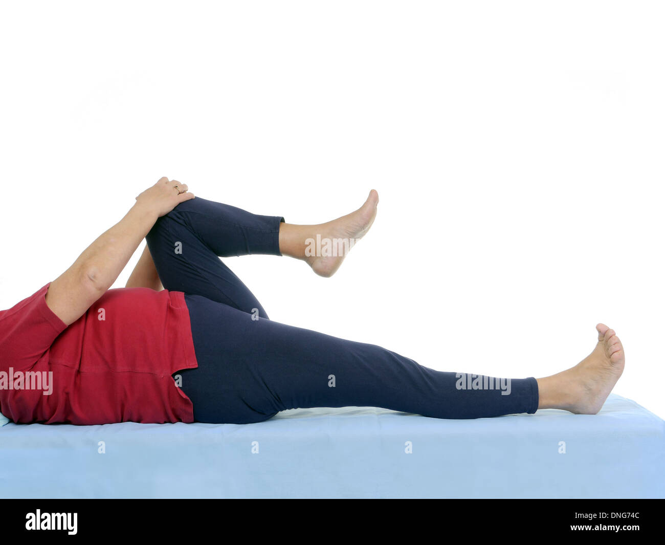 Older patient performing functional test of hip joint contraction lying on bed Stock Photo