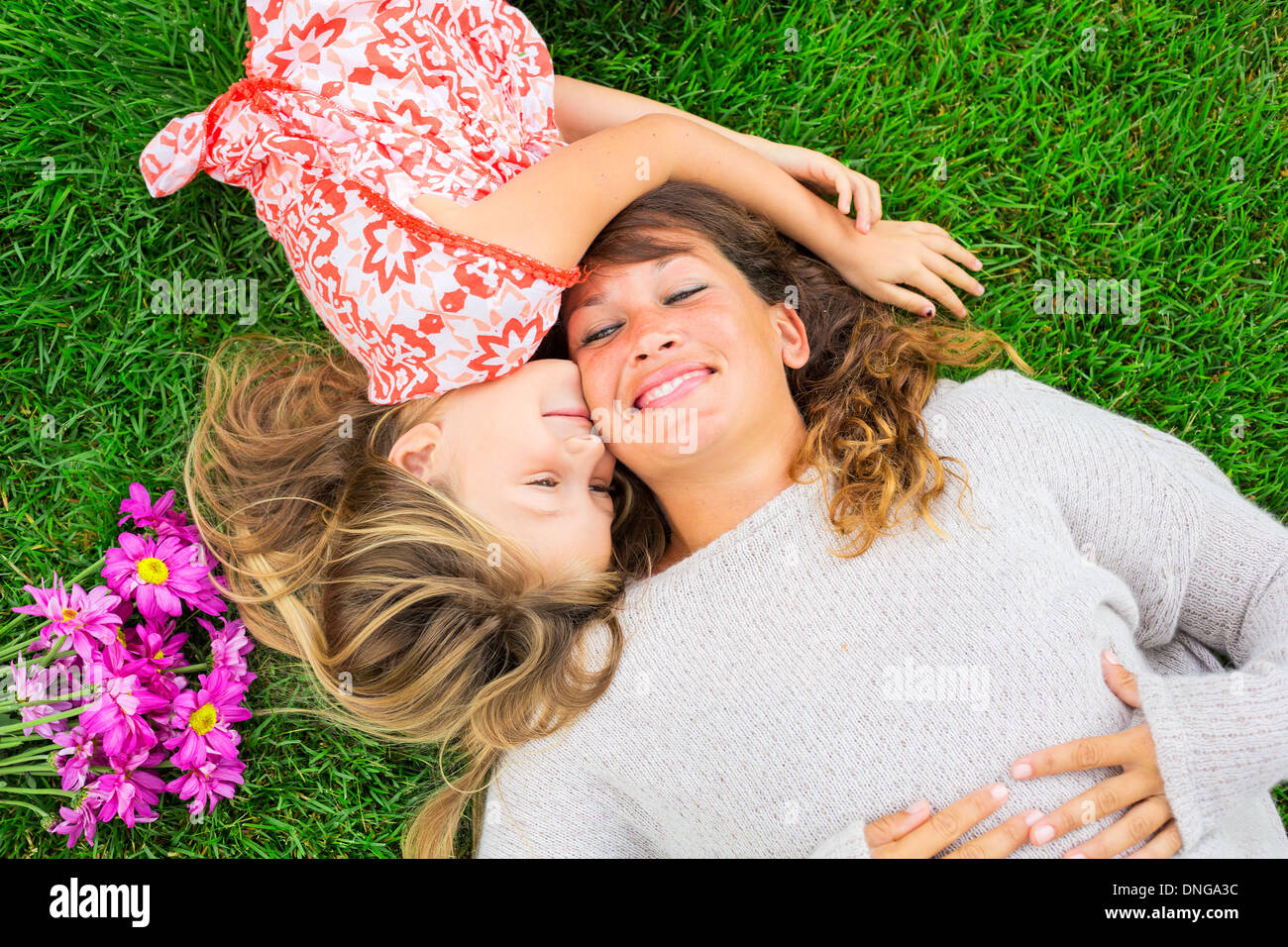 Beautiful Mother And Daughter Lying Together Outside On Grass Happy