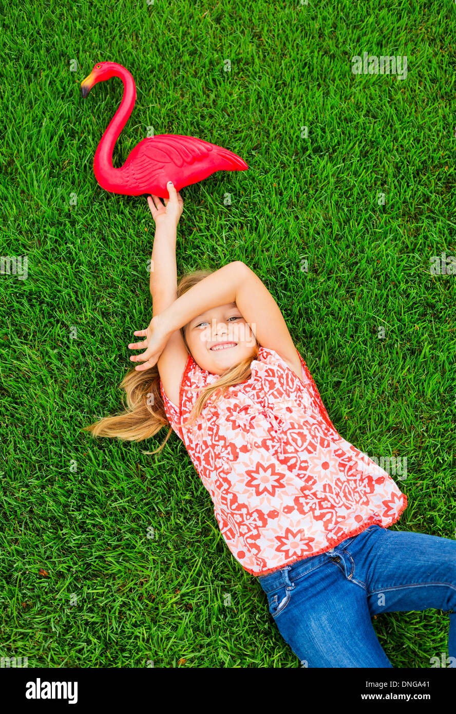 Cute happy little girl smiling outside dying on the grass with flamingo ...