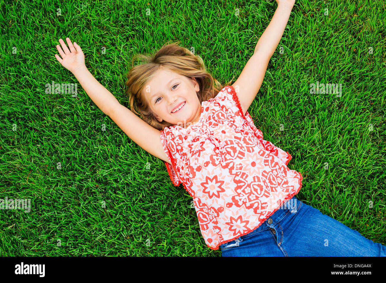 Cute happy little girl smiling outside lying on the grass Stock Photo ...