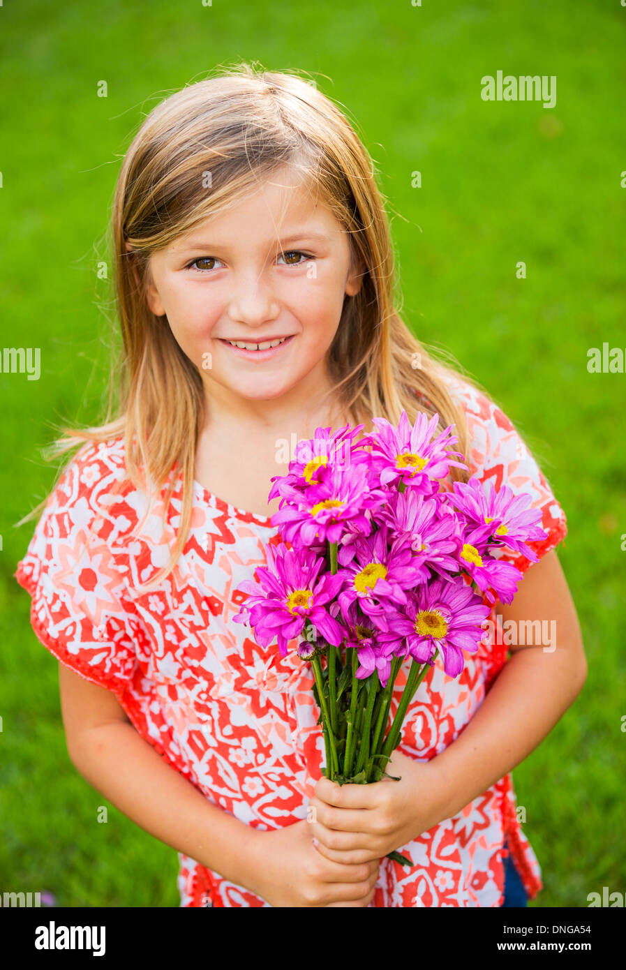 Cute happy little girl smiling outside with spring flowers Stock Photo ...