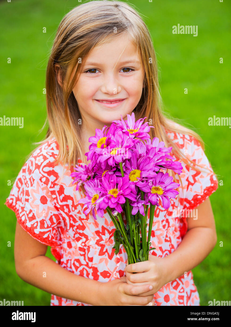 Cute happy little girl smiling outside with spring flowers Stock Photo ...