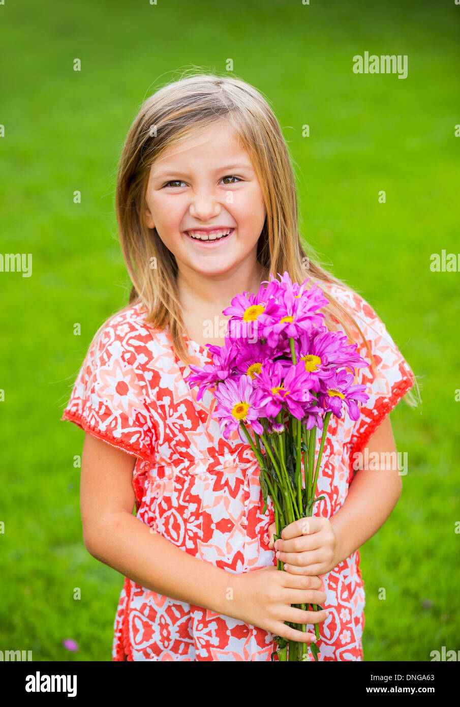 Cute happy little girl smiling outside with spring flowers Stock Photo ...
