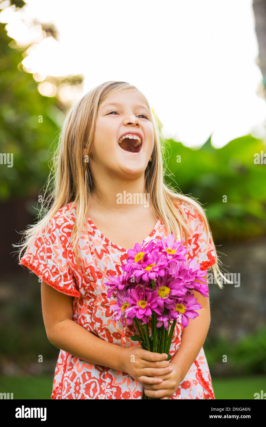 Cute happy little girl smiling outside with spring flowers Stock Photo ...