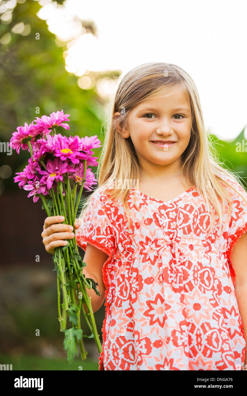 Cute happy little girl smiling outside with spring flowers Stock Photo ...