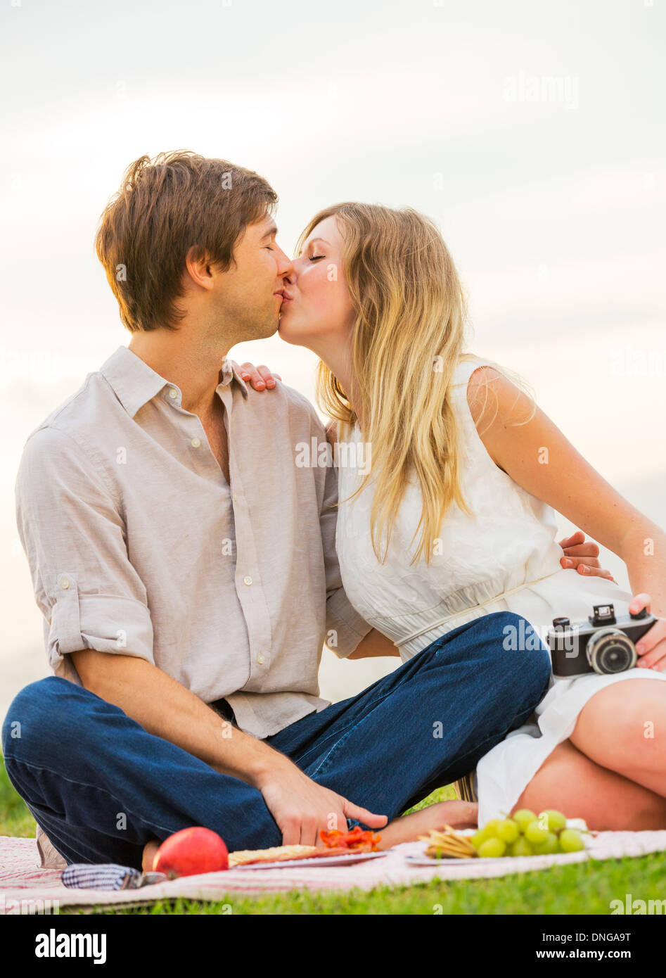 Picture of Attractive couple kissing on romantic afternoon picnic in countryside ...