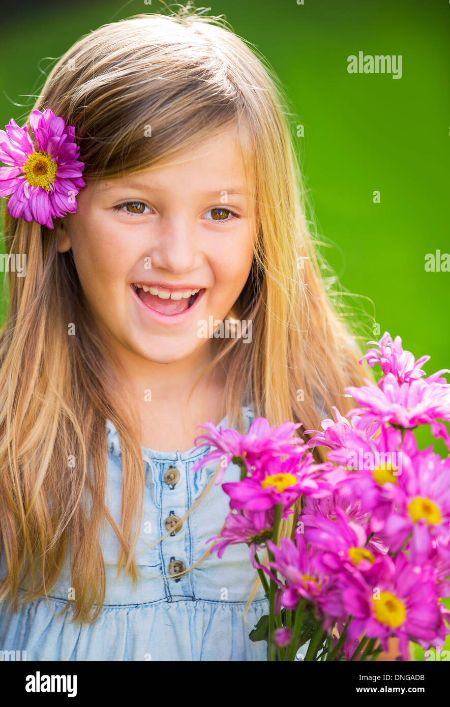 Cute happy little girl smiling outside with spring flowers Stock Photo ...