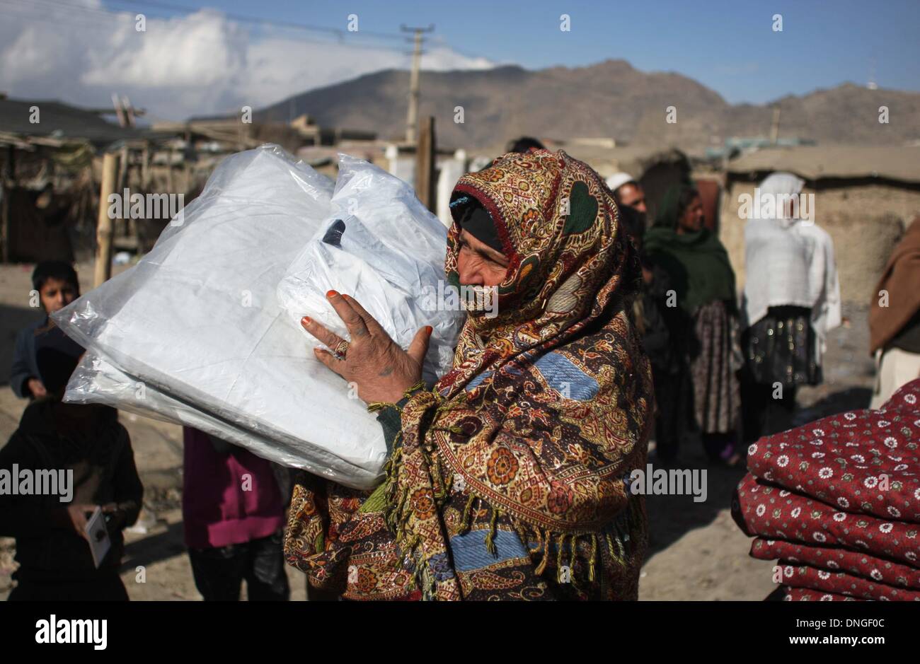 Kabul, Afghanistan. 28th Dec, 2013. An Afghan woman carries winter relief supplies donated by German government for displaced people in Kabul, Afghanistan, Dec. 28, 2013. © Ahmad Massoud/Xinhua/Alamy Live News Stock Photo