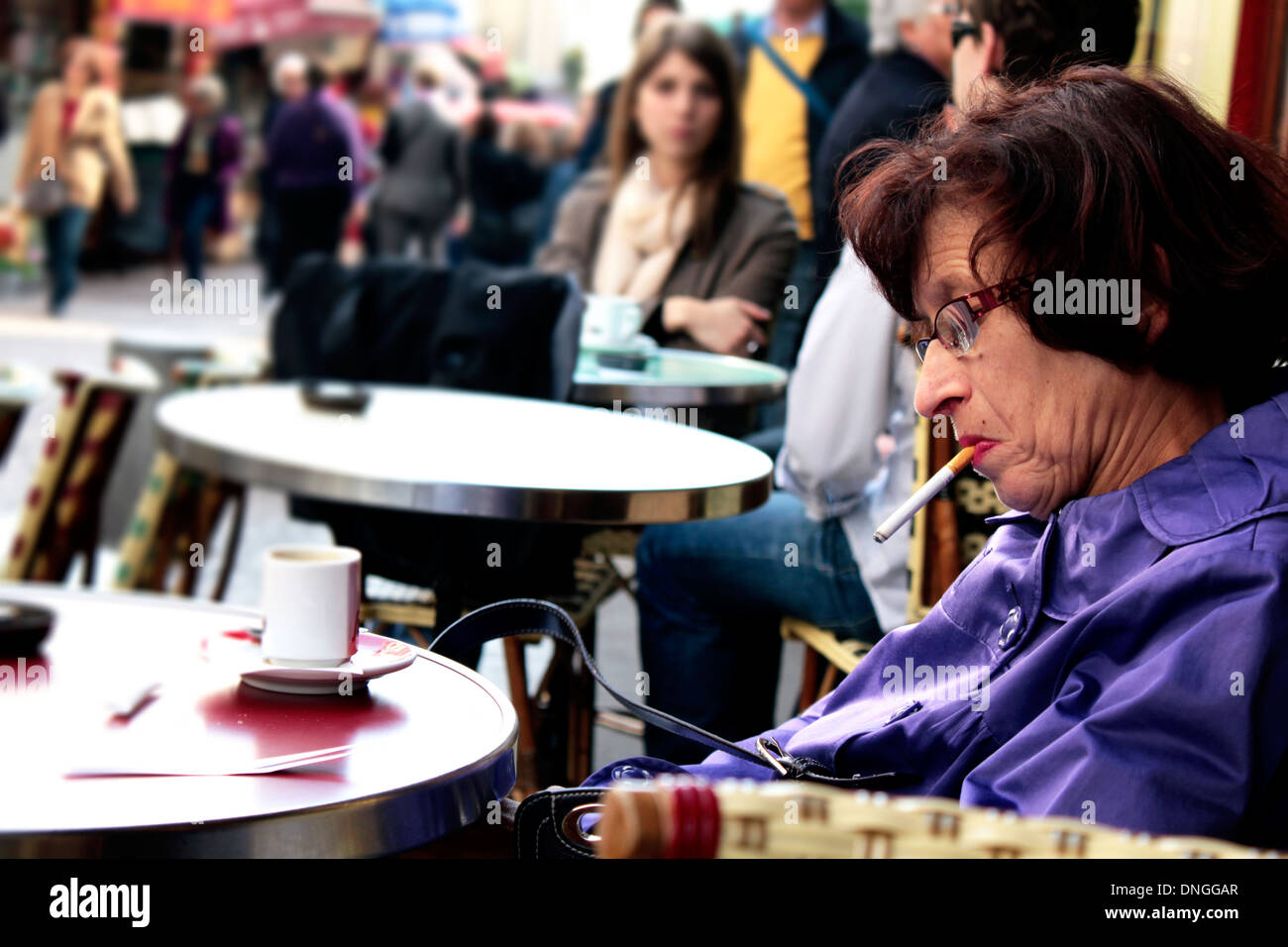 Middle age Parisian lady smoking and drinking coffe in the outdoors street café rue Mouffetard, Paris Stock Photo