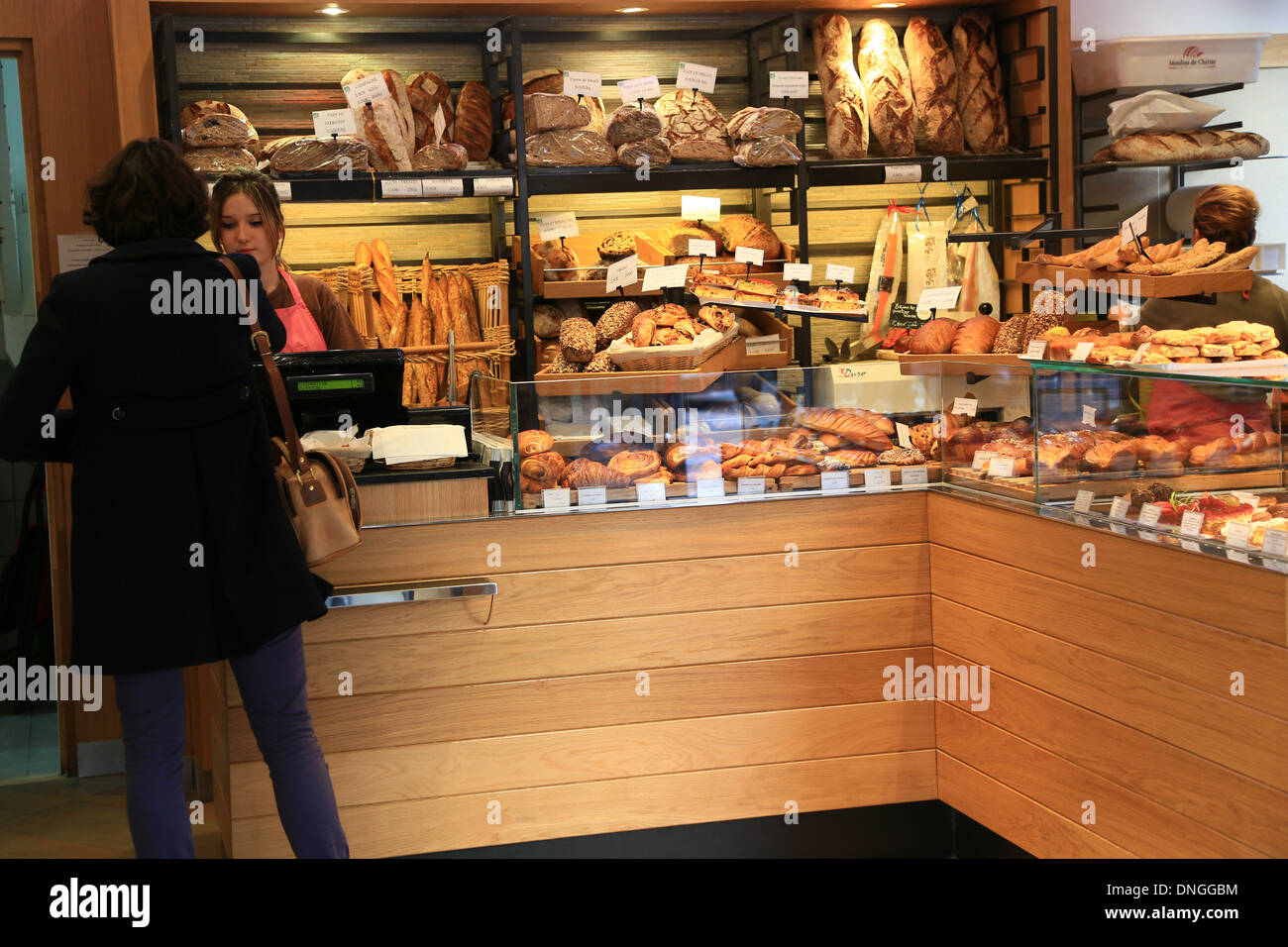 Baker woman is taking care of the customer in the typical French bakery at rue Mouffetard in Paris, France Stock Photo