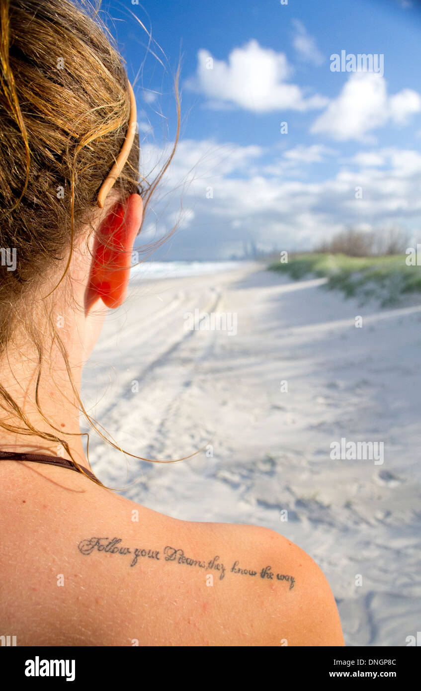 A tattoo saying 'Follow your dreams, they know the way' on a shoulder of a female Stock Photo