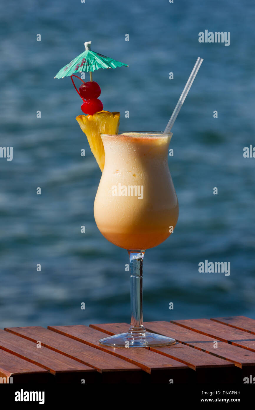 pina colada served on the beach garnished with fresh pineapple and cherries Stock Photo