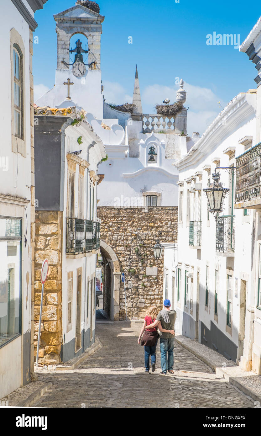 young couple walking down a cobblestone street in the historical part of faro, algarve, portugal Stock Photo