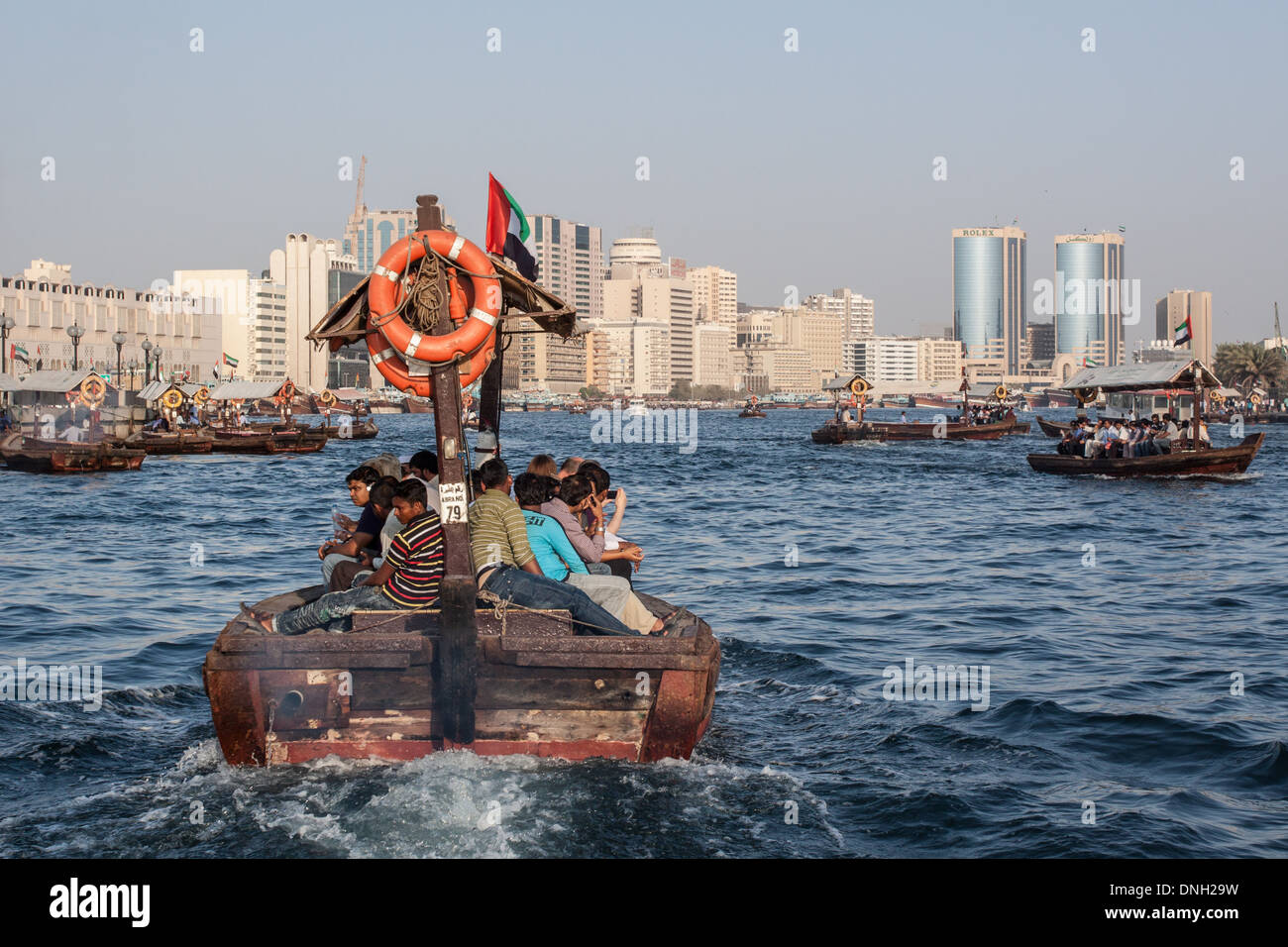 TRADITIONAL BOAT, THE ABRA, CROSSING THE DUBAI CREEK WITH THE ROLEX TOWERS IN THE BACKGROUND, DUBAI, UNITED ARAB EMIRATES, MIDDLE EAST Stock Photo