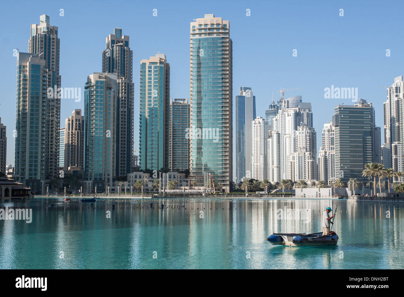 WORKERS CLEANING THE POND NEXT TO THE DUBAI MALL IN THE SHADE OF THE HIGHRISES OF THE BUSINESS BAY NEIGHBORHOOD, DOWNTOWN DUBAI, DUBAI, UNITED ARAB EMIRATES, MIDDLE EAST Stock Photo