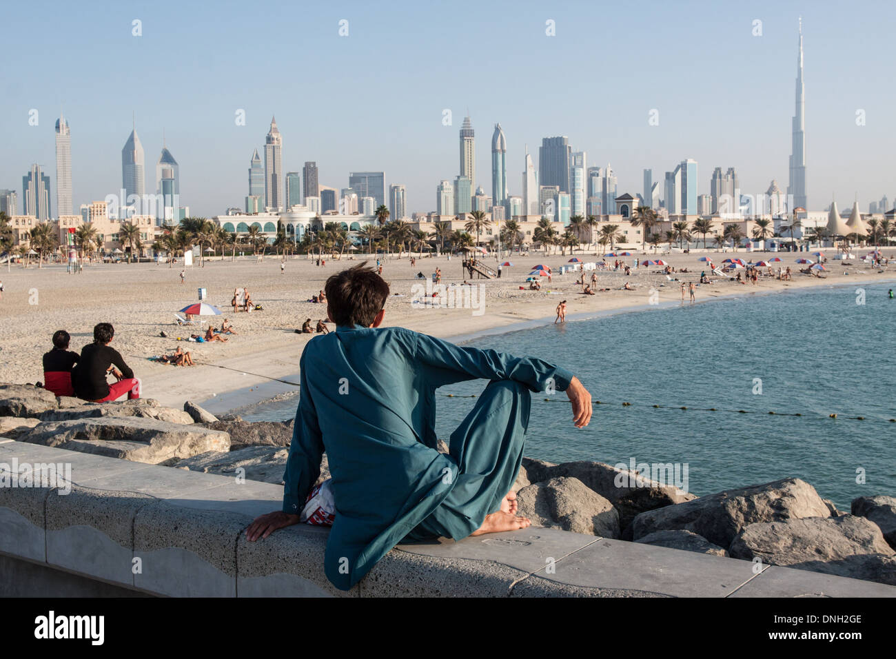 MAN LOOKING AT THE BEACH AND THE SKYLINE OF SHEIKH ZAYED ROAD WITH THE FINANCIAL CENTER AND DOWNTOWN DUBAI DOMINATD BY THE BURJ KHALIFA TOWER, ONCE KNOWN AS BURJ DUBAI, DUBAI, UNITED ARAB EMIRATES, MIDDLE EAST Stock Photo