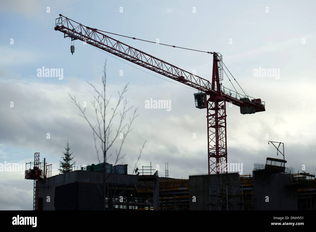 A silhouetted crane at a construction site. Stock Photo