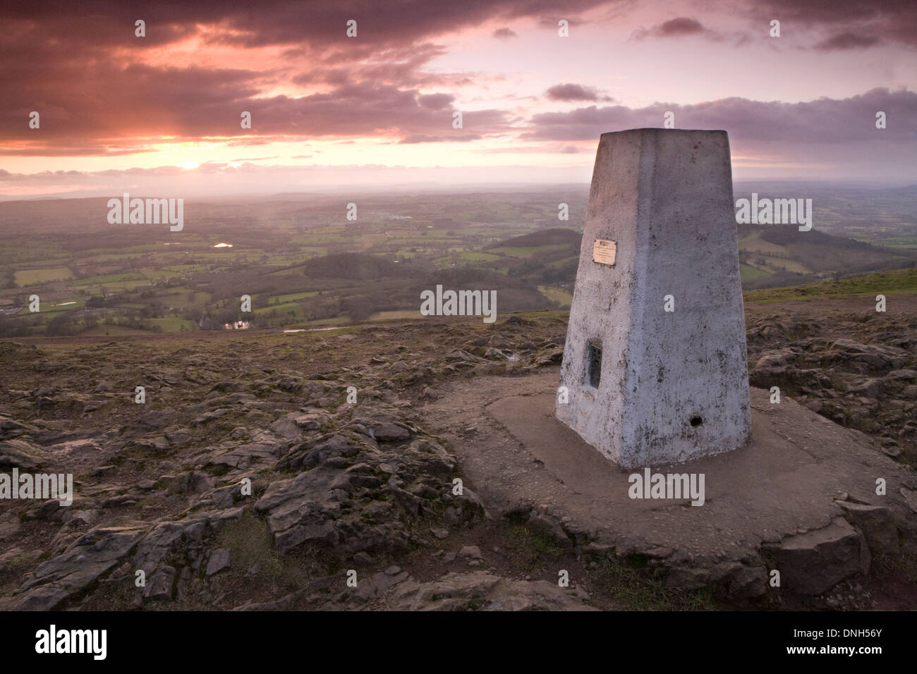 The OS Trig point stands tall on the Worcestershire Beacon on the Malvern Hills at sunset. Stock Photo