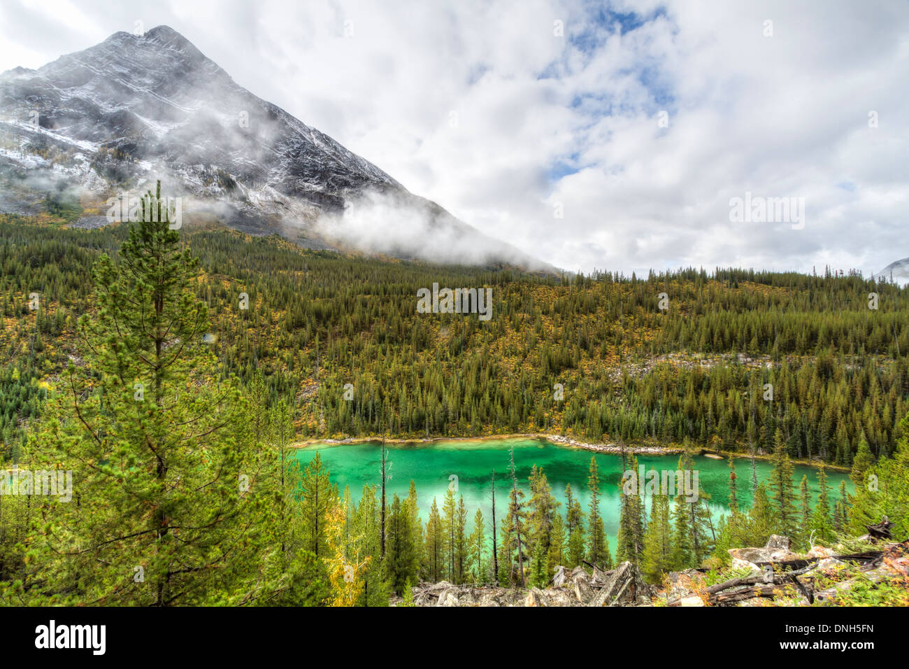 Storm Mountain emerges from the fog and clouds above emerald Vista Lake in Banff National Park, Canada Stock Photo