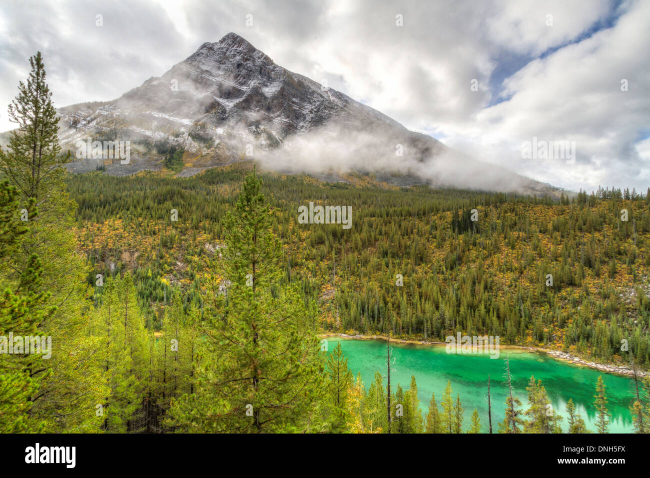 Storm Mountain emerges from the fog and clouds above emerald Vista Lake in Banff National Park, Canada Stock Photo