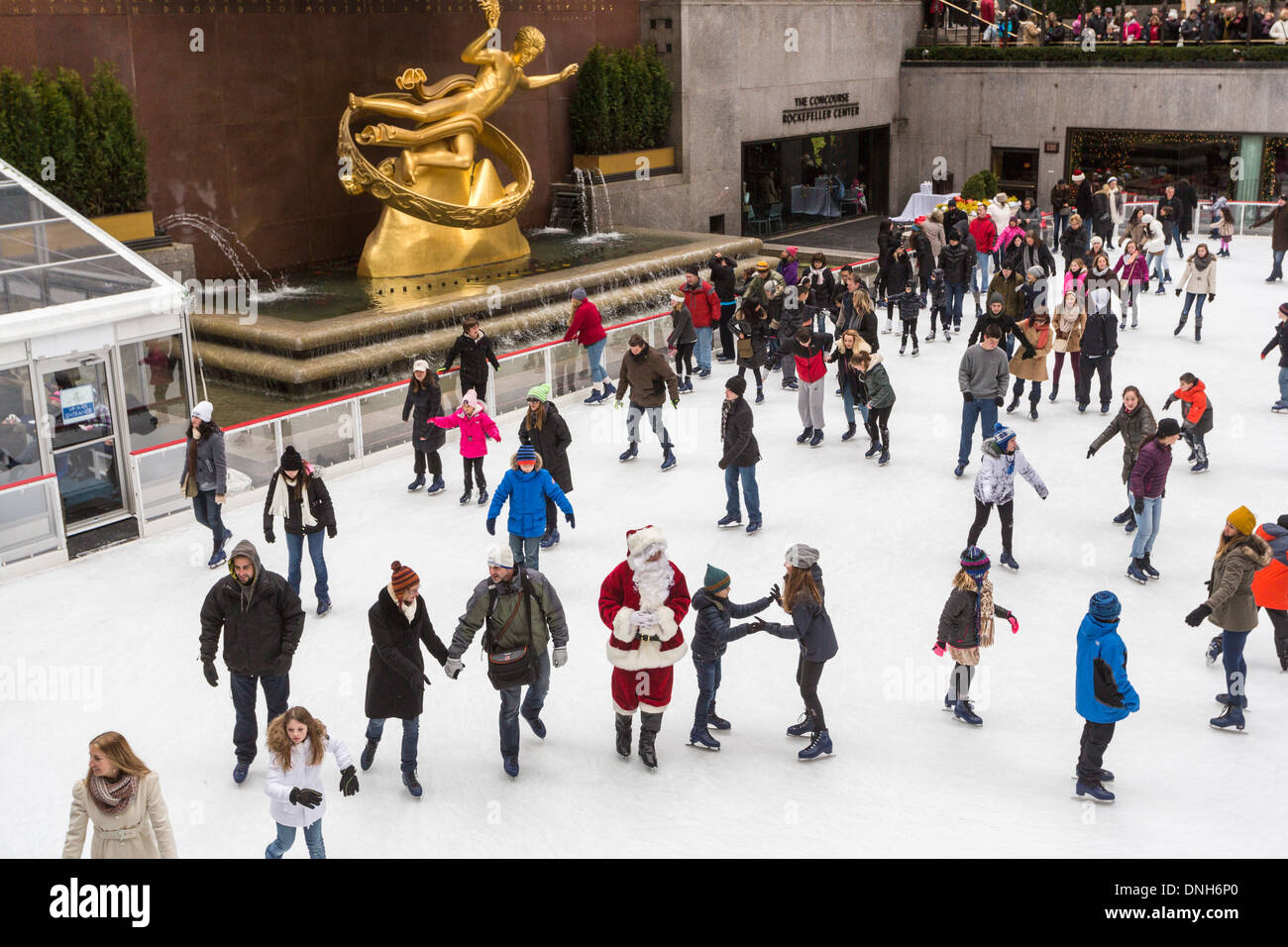 Ice skaters skating on the ice rink at The Concourse at the Rockefeller Center, New York, USA, with traditional Santa Claus Stock Photo