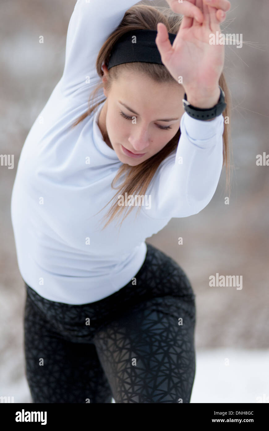 A beautiful young woman in tights stretches before a run on a cold, winter day. Stock Photo