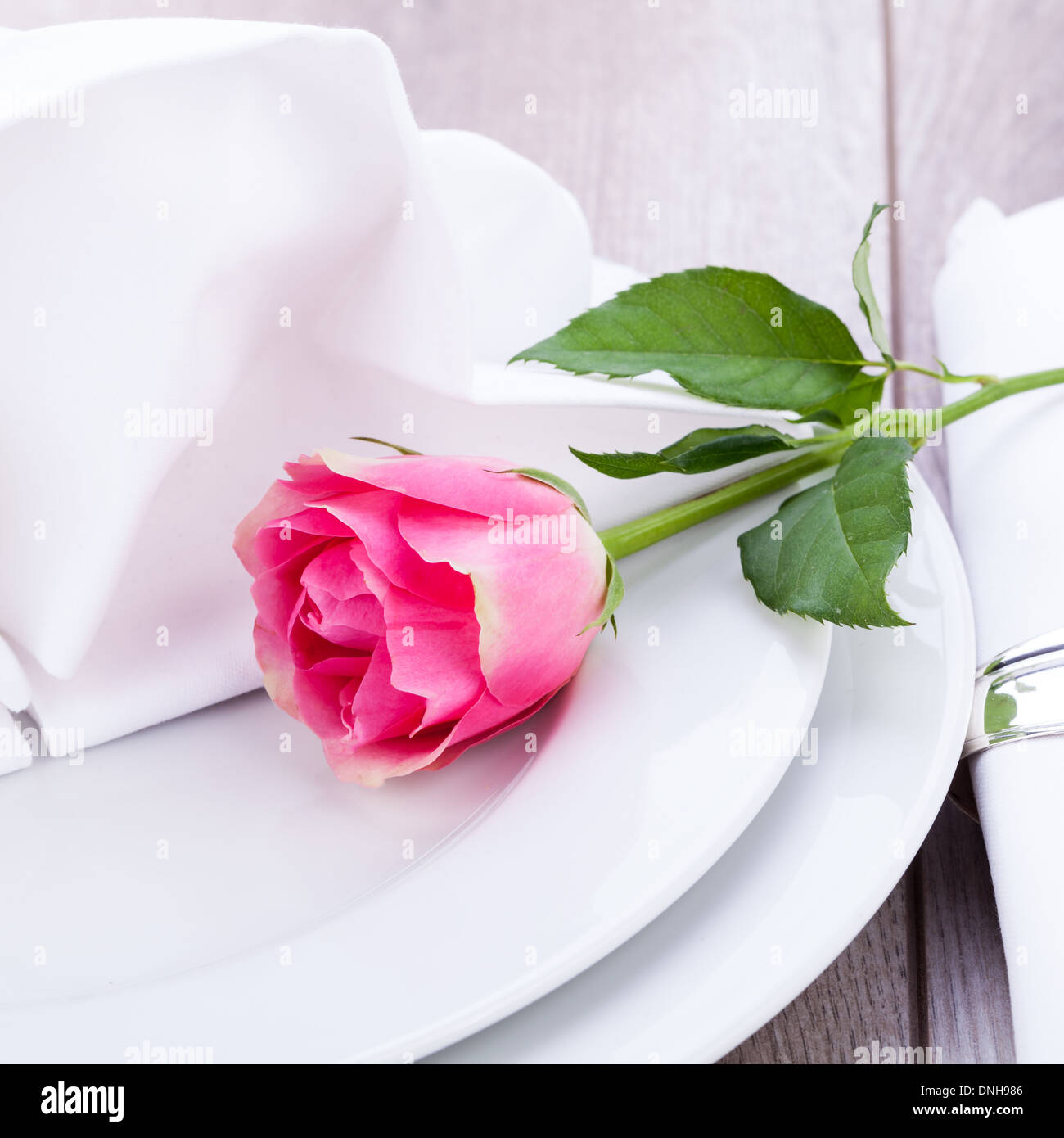 Romantic formal elegant table setting with a single pink rose and ...