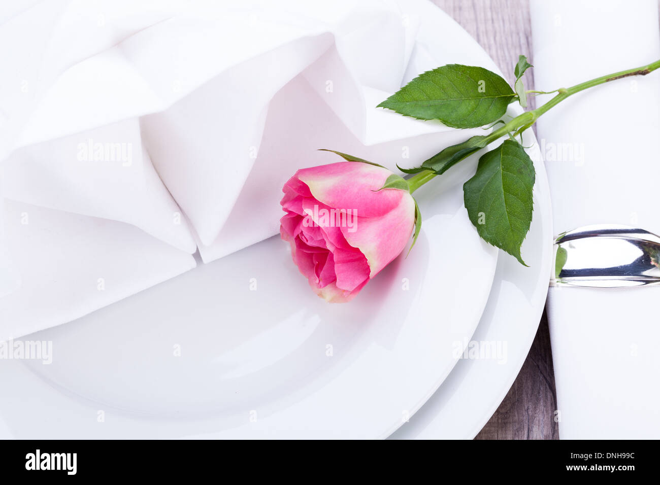Romantic formal elegant table setting with a single pink rose and ...