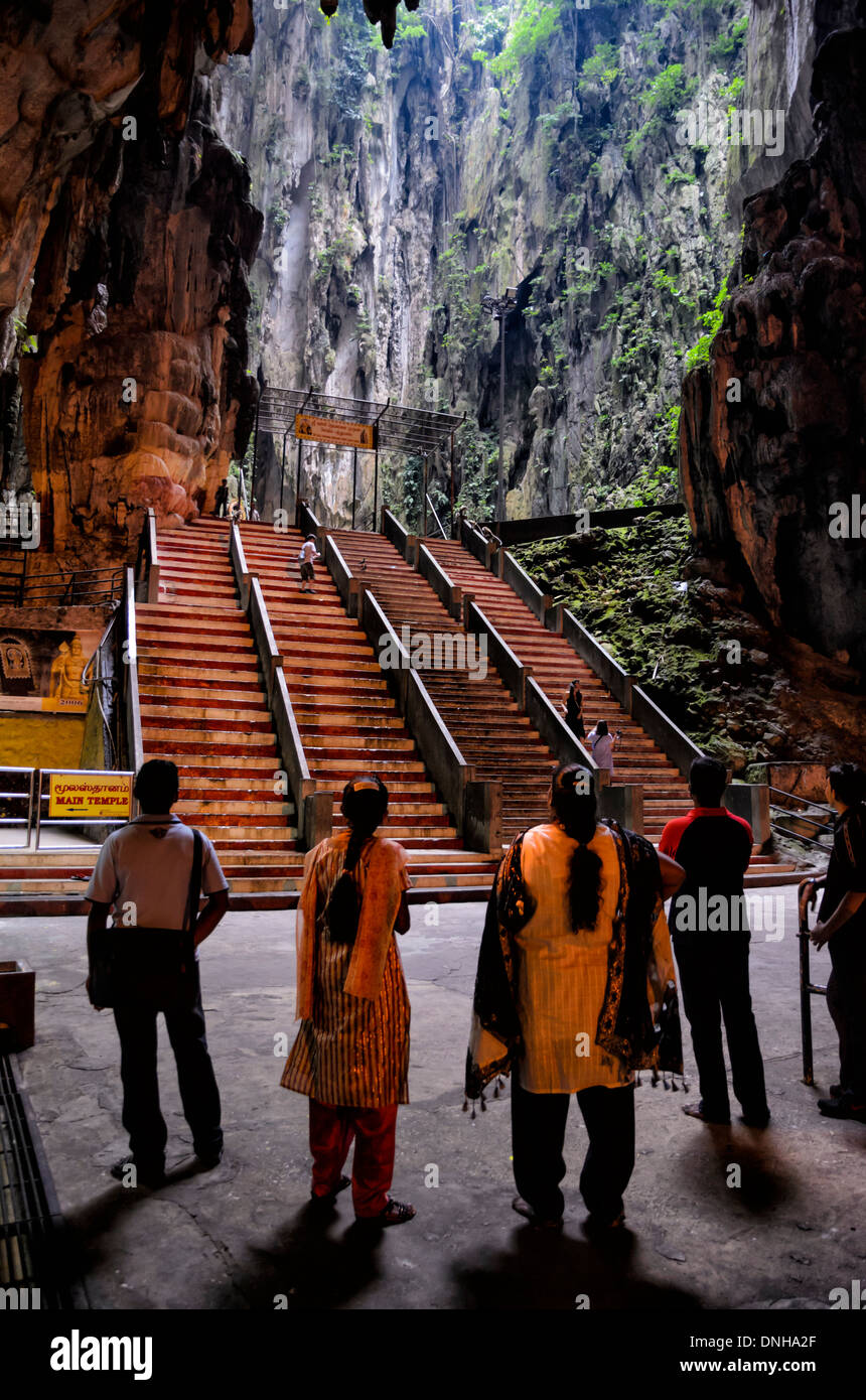 Hindu pilgrims dressed in traditional clothes visiting a cave temple. Stock Photo