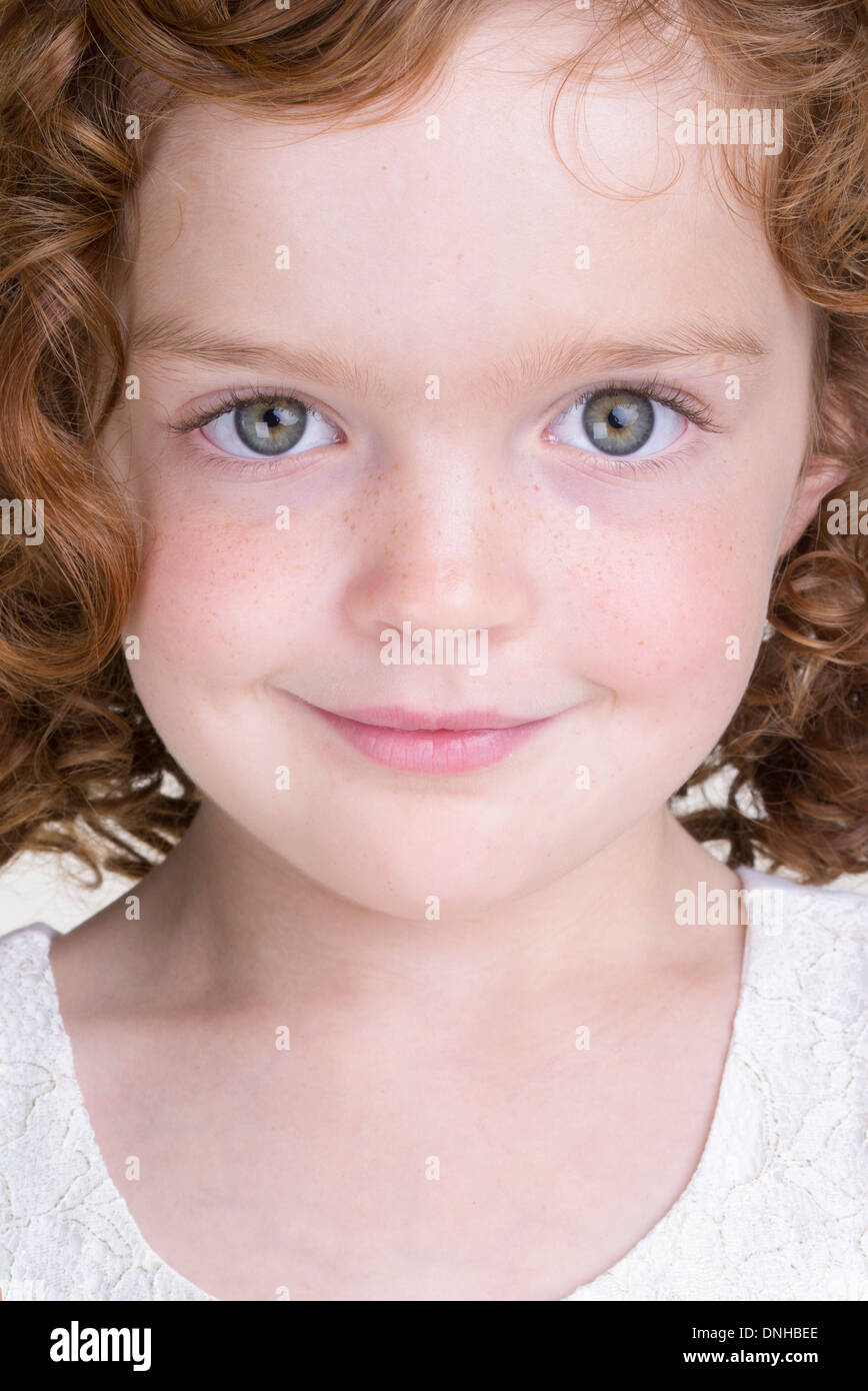 Close up portrait of smiling young girl with curly red hair similar to Annie Stock Photo
