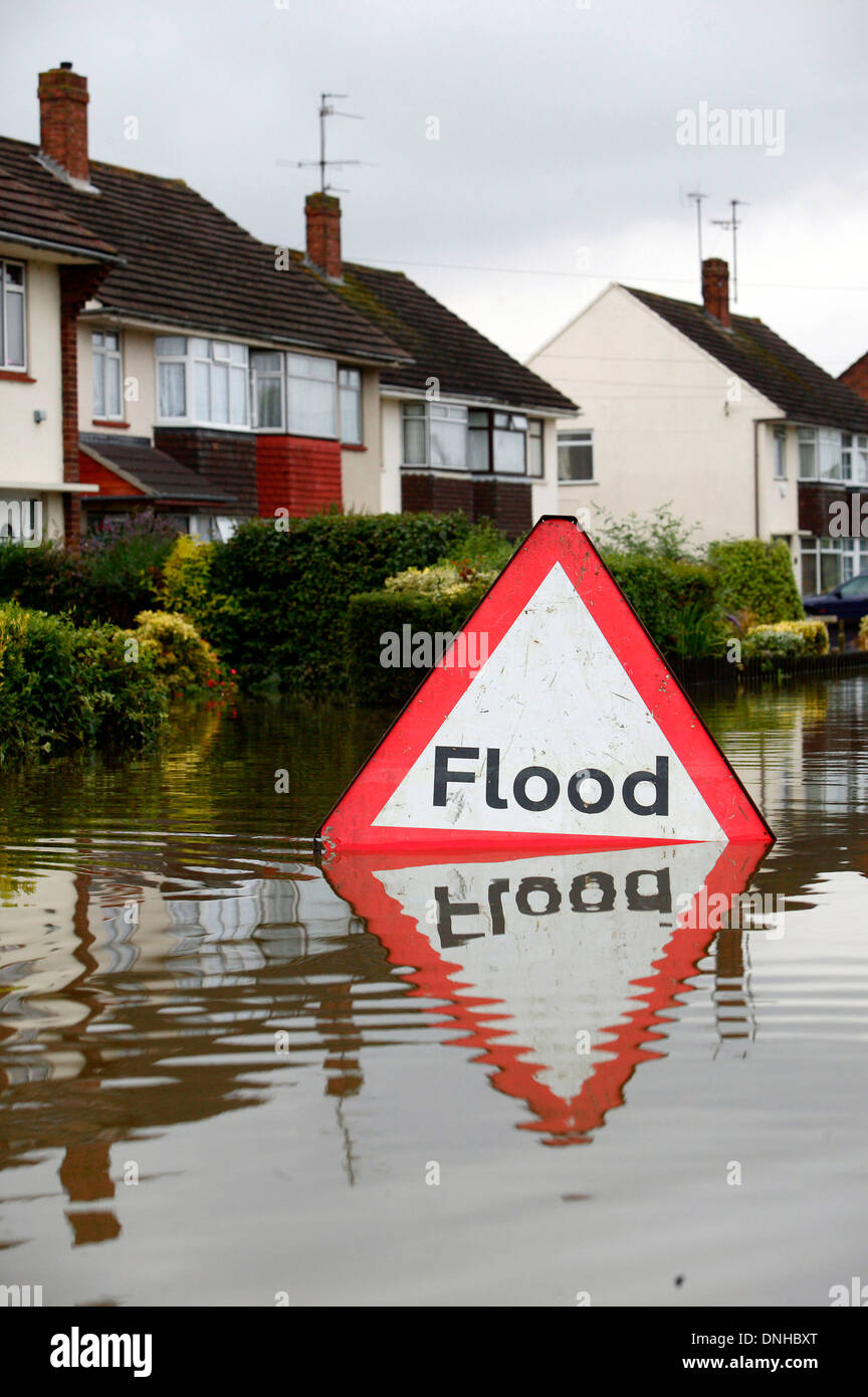 A flood hazard warning sign is pictured in water near flooded homes in