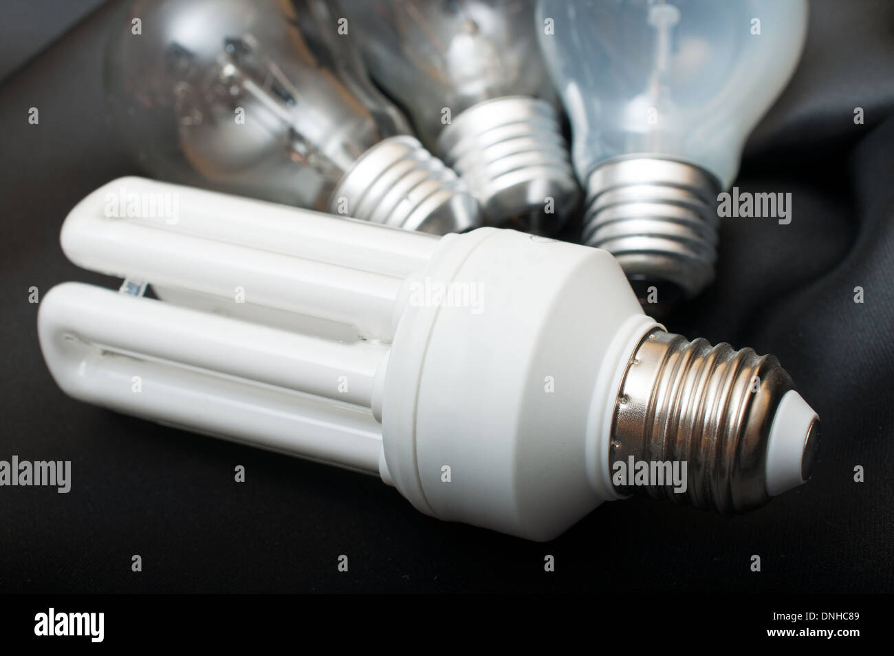 Energy Saving Bulb and Three Aged Burnt Tungsten Bulbs on Black Background Stock Photo