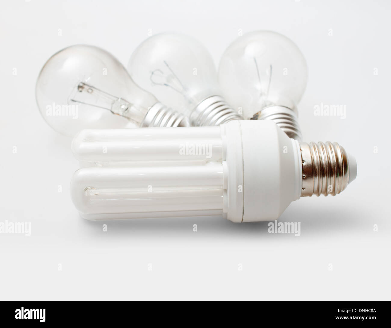 New Energy Saving Bulb and Three Aged Burnt Tungsten Bulbs on Light Background Stock Photo