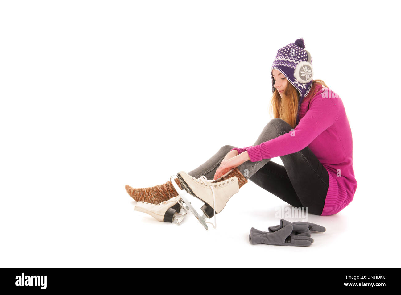 Attractive woman in pink put on the ice skates isolated over white background Stock Photo