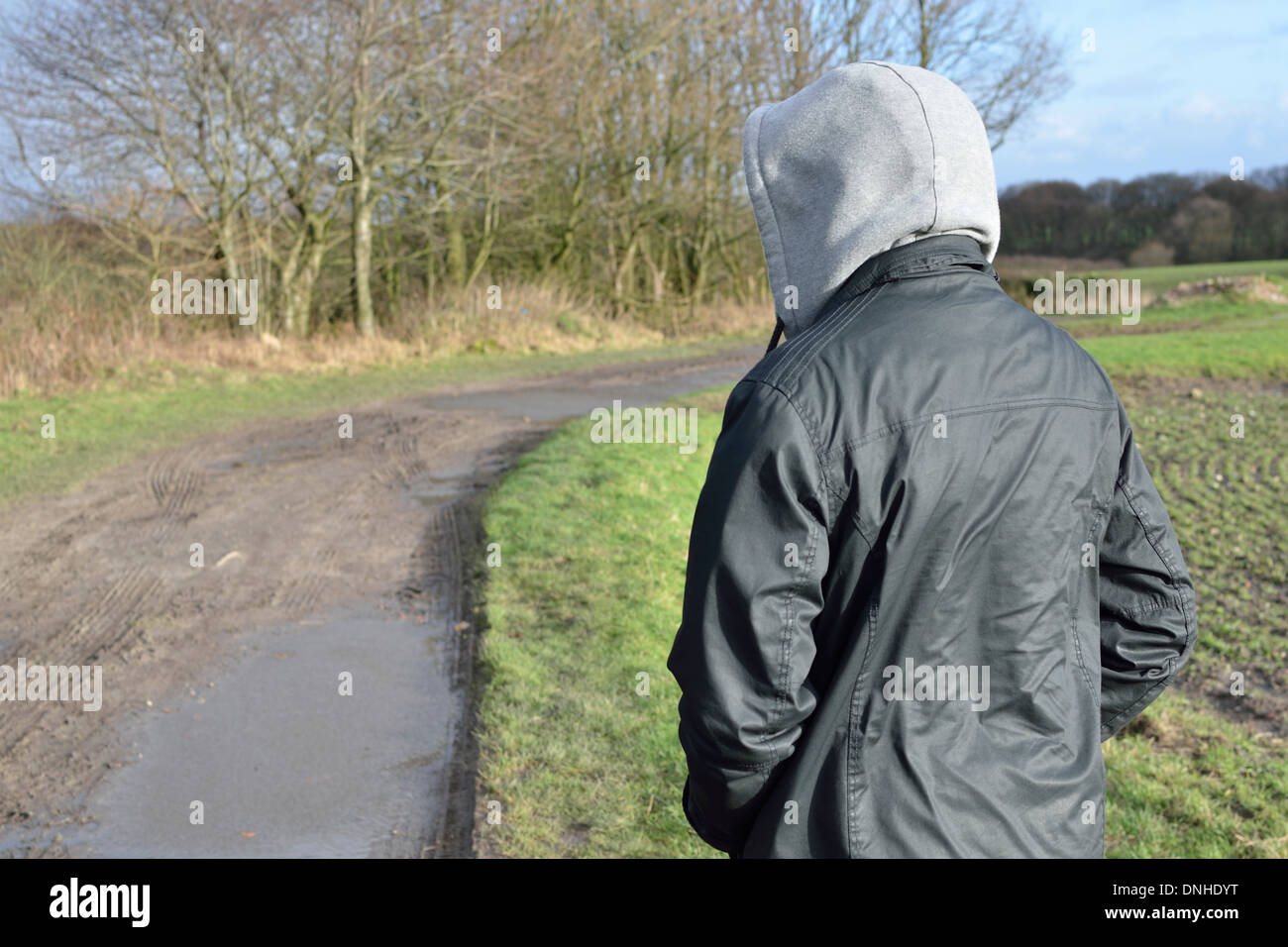 Man in hooded jacket on wet country path Stock Photo