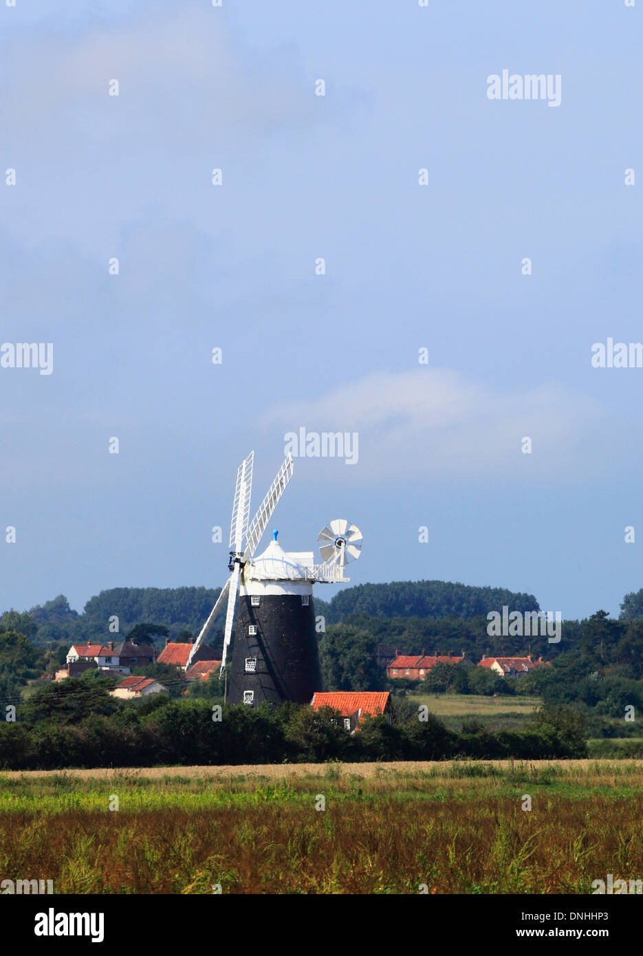 The windmill at Burnham Overy on the Norfolk coast with boats in the sea and marshland behind. Stock Photo