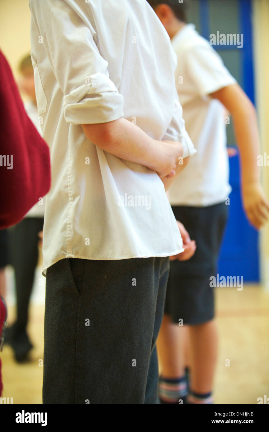 two school boys stand in a primary school at assembly Stock Photo