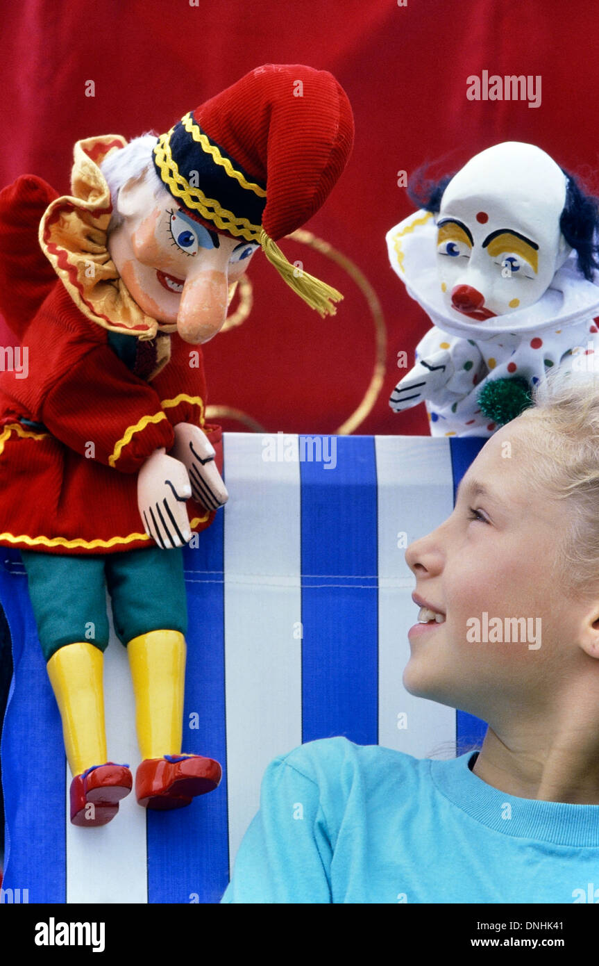 Mr Punch and Joey the clown entertain a tween girl sitting in a deckchair Stock Photo