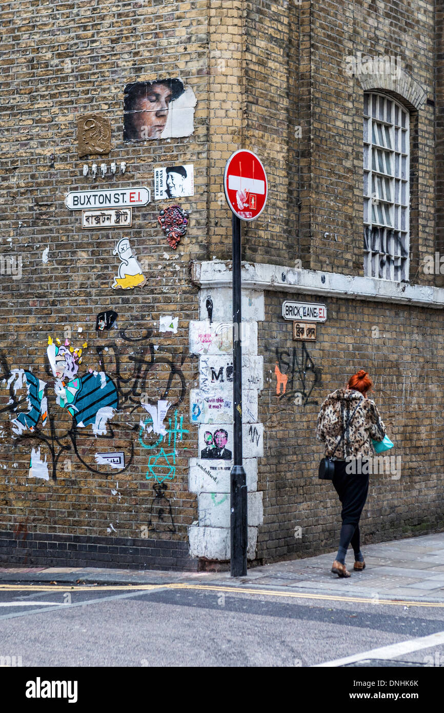 Woman with red hair, no entry sign and  street art and graffiti on corner of Buxton street and Brick lane, East London, UK Stock Photo