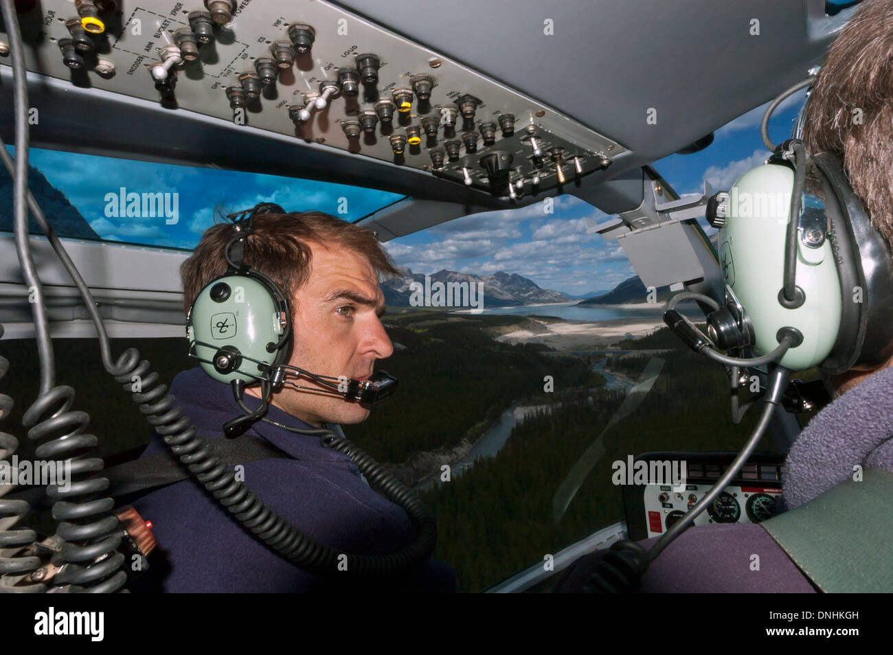 Pilot and passenger wearing headphones in helicopter cockpit, Alberta