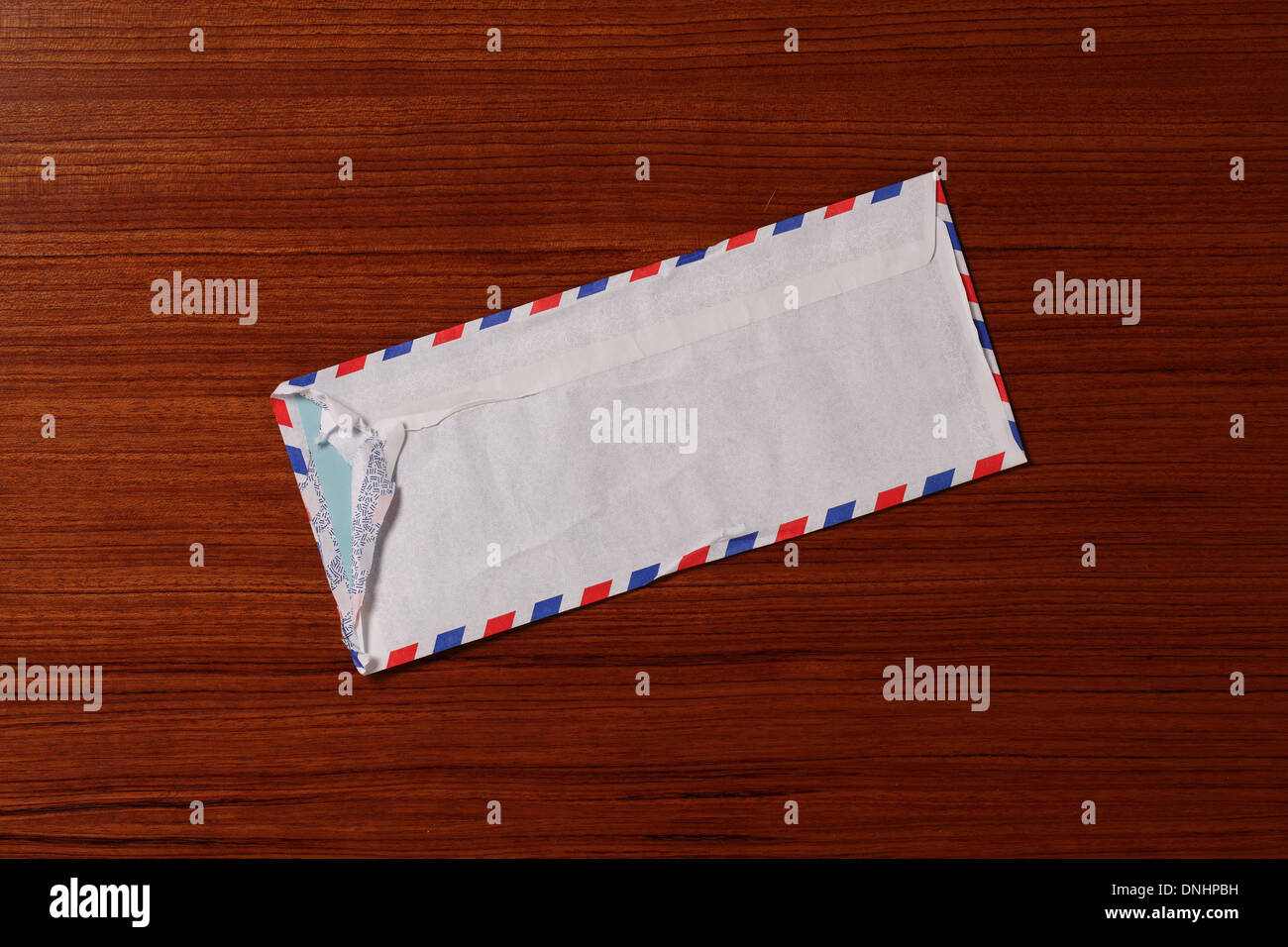 An air mail postage envelope slightly worn and torn on a wood surface. Stock Photo