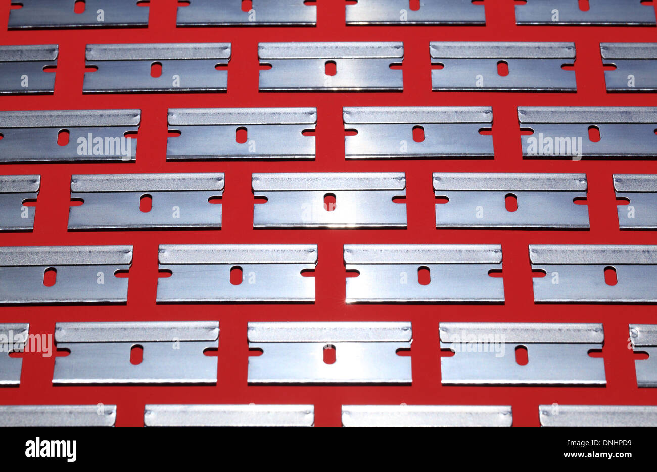 A pattern of many metal razor blades on a red background. Stock Photo