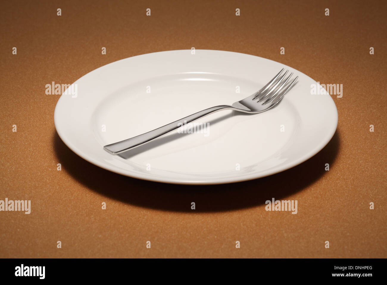 A dinning fork on a empty white dinning plate. Stock Photo