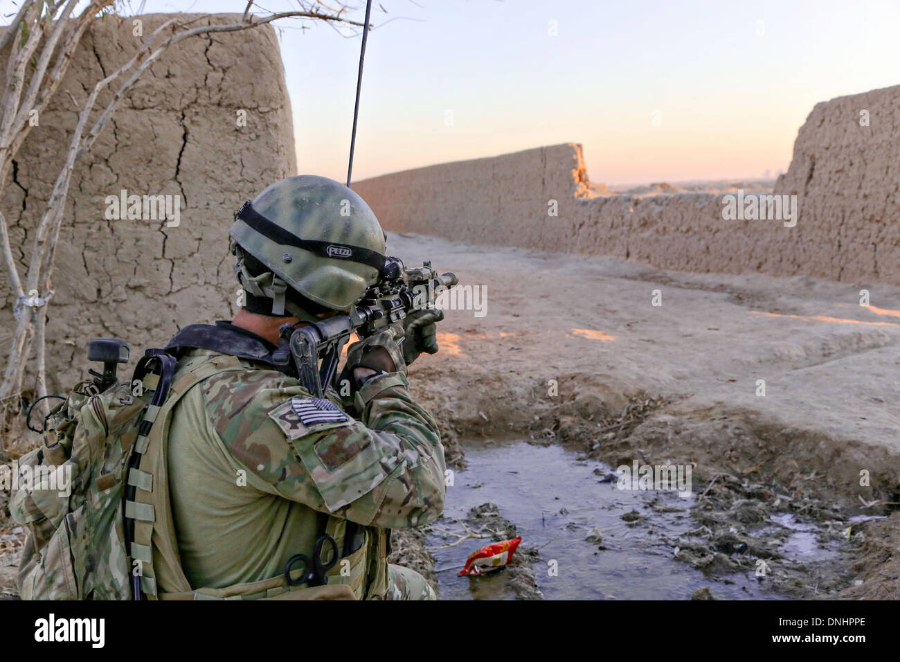 A US special operations Soldier scans the area as Afghan National Army commandos conduct a patrol December 27, 2013 in Mandozai village, Maiwand district, Kandahar province, Afghanistan. Stock Photo