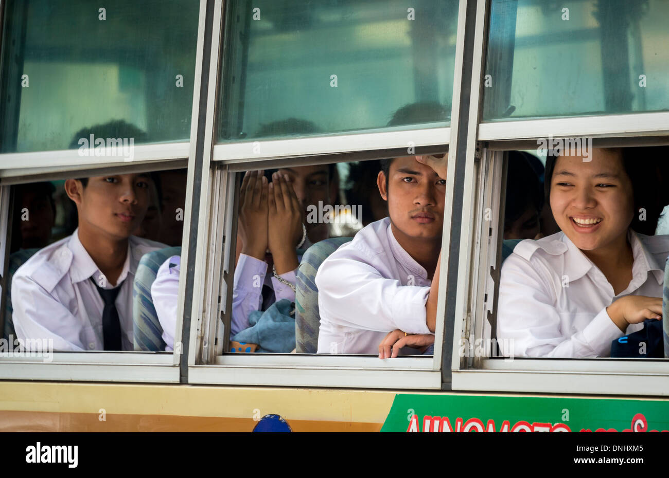 YANGON, MYANMAR - CIRCA DECEMBER 2013: Passengers looking through a bus window in a busy street in Yangon. Stock Photo