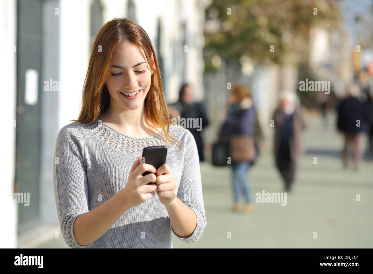 Portrait of a beautiful casual woman in the street browsing a smart phone Stock Photo