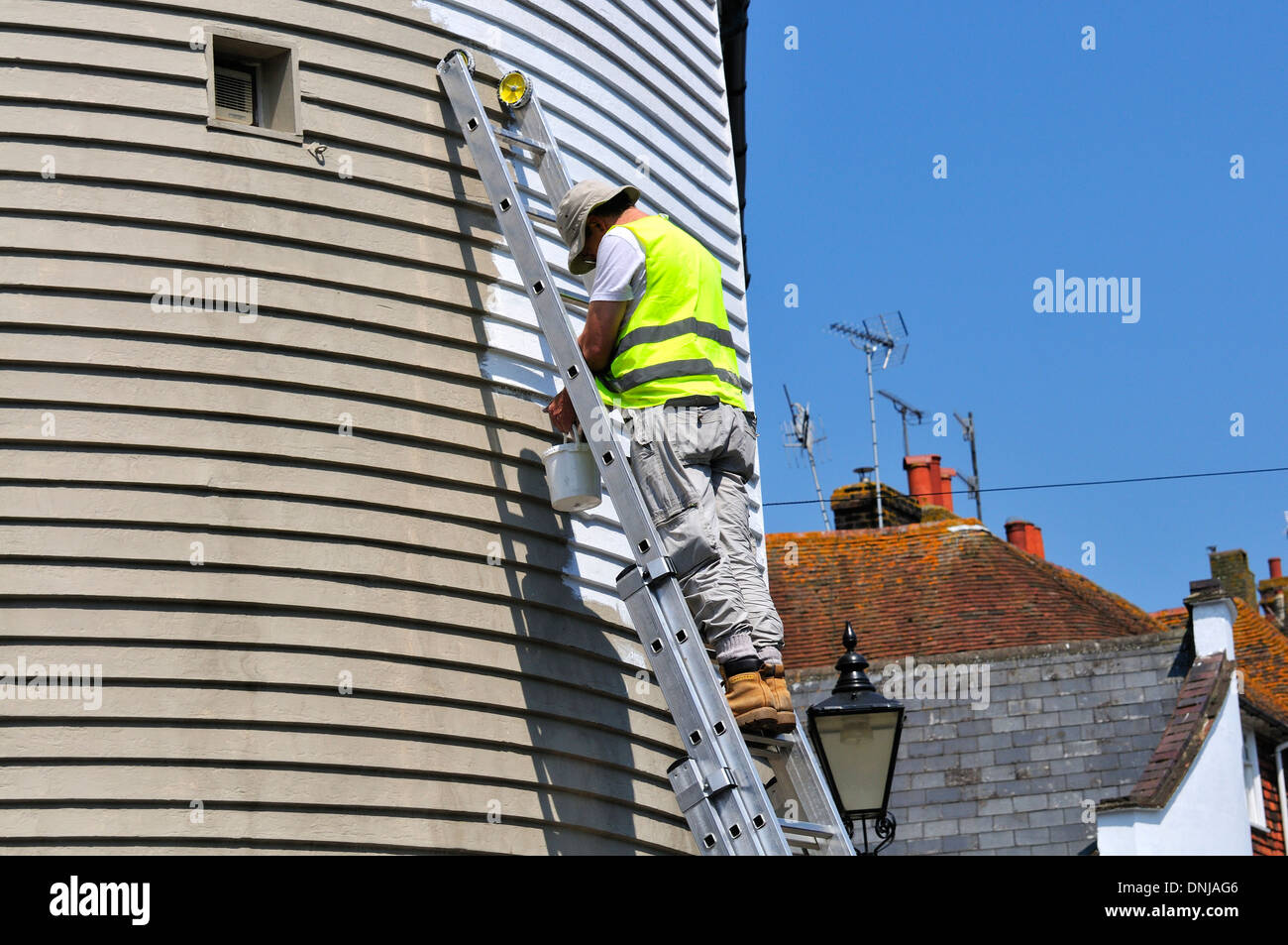 Rye, East Sussex, England, UK. Man repainting weatherboarding after having been painted grey for use as a film set Stock Photo