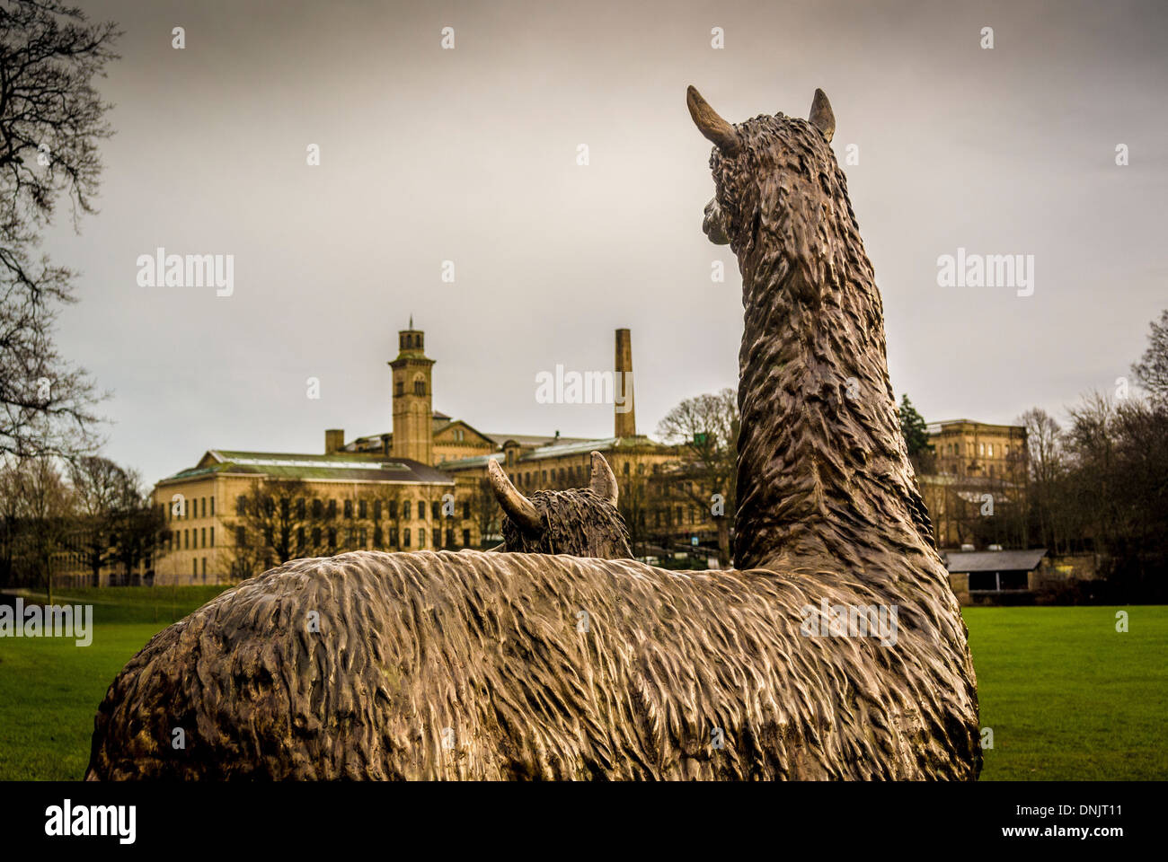 Roberts Park's statue of Alpacas seen from behind with New Mill and Salts Mill in the distance.  Saltaire, West Yorkshire. Stock Photo