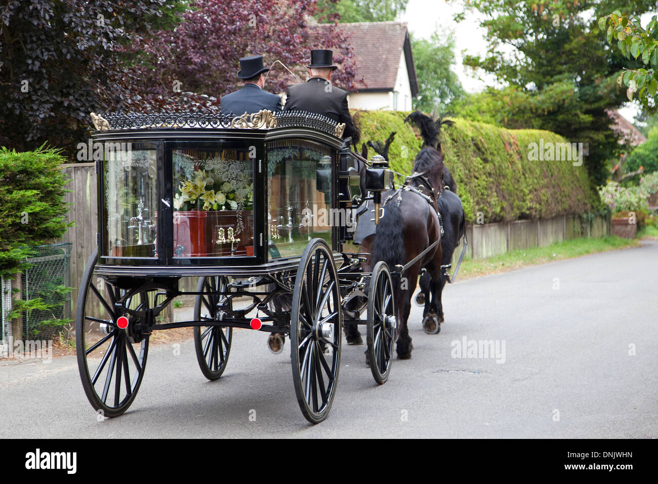 Traditional horsedrawn hearse carrying coffin on route to church Stock