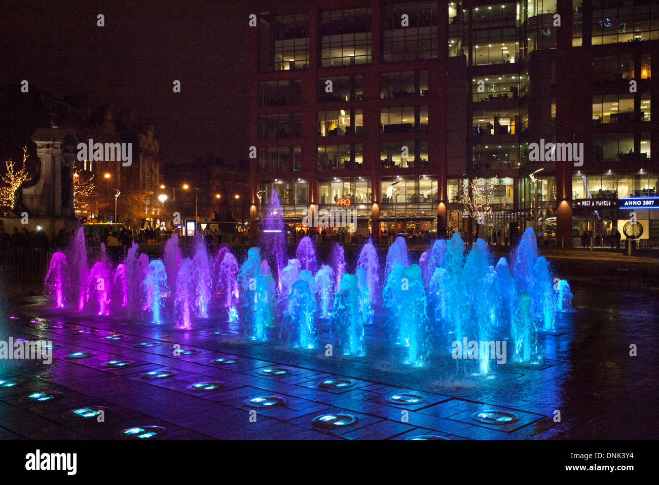 Blue illuminated coloured fountains in Piccadilly Gardens as Manchester's hosted privately sponsored New Year's Eve celebrations and fireworks display, with Big Wheel and Michael Jackson’s Thriller helping usher in 2014. Stock Photo